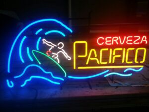 A neon sign that says cerveza pacifico with a surfer riding the wave.