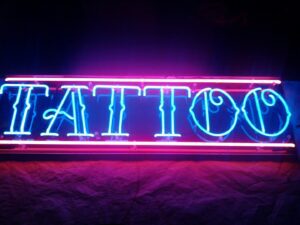 A neon sign that says tattoo in blue light.