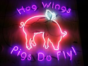 A neon sign that says hog wings pigs do fly