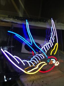 A neon sign of a bird with wings spread.