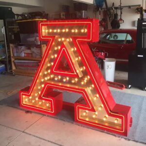 A large red letter sign with lights on top of it.